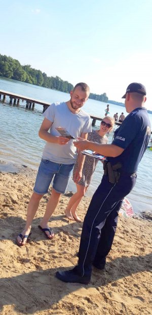 Policjanci z Cekcyna przekazują materiały profilaktyczne do akcji &quot;Kręci mnie bezpieczeństwo nad wodą&quot; nad jeziorem Cekcyńskim.